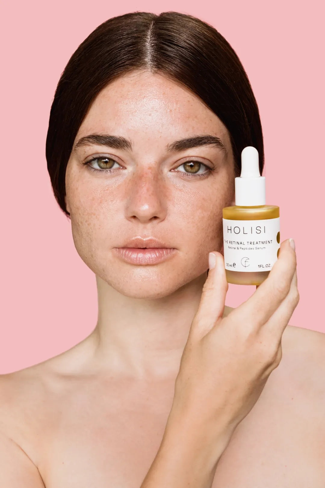 Frasco del sérum antiedad The Retinal Treatment de Holisi sobre la mano de modelo