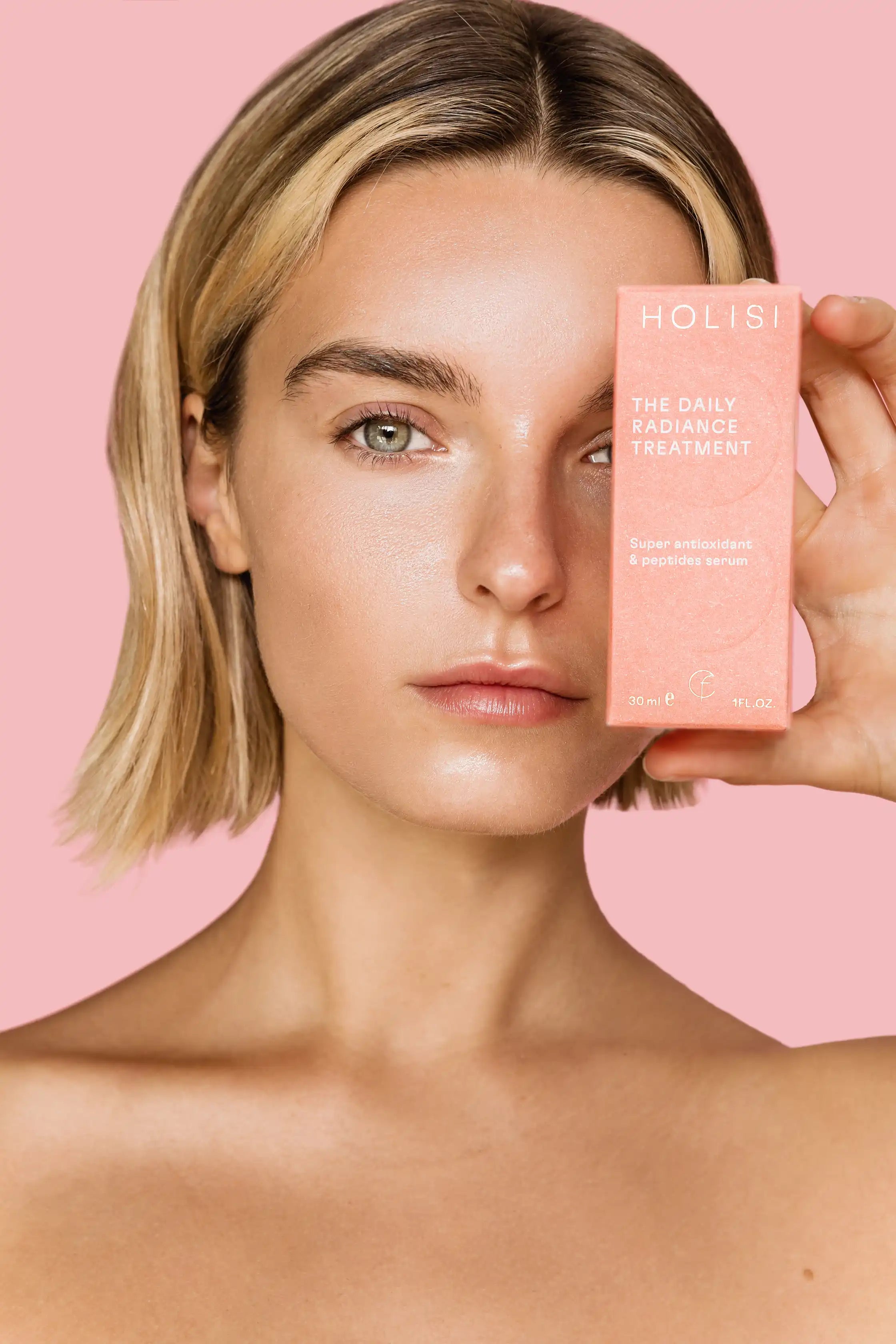 Modelo sosteniendo la caja del sérum con vitamina C The Daily Radiance Treatment de Holisi