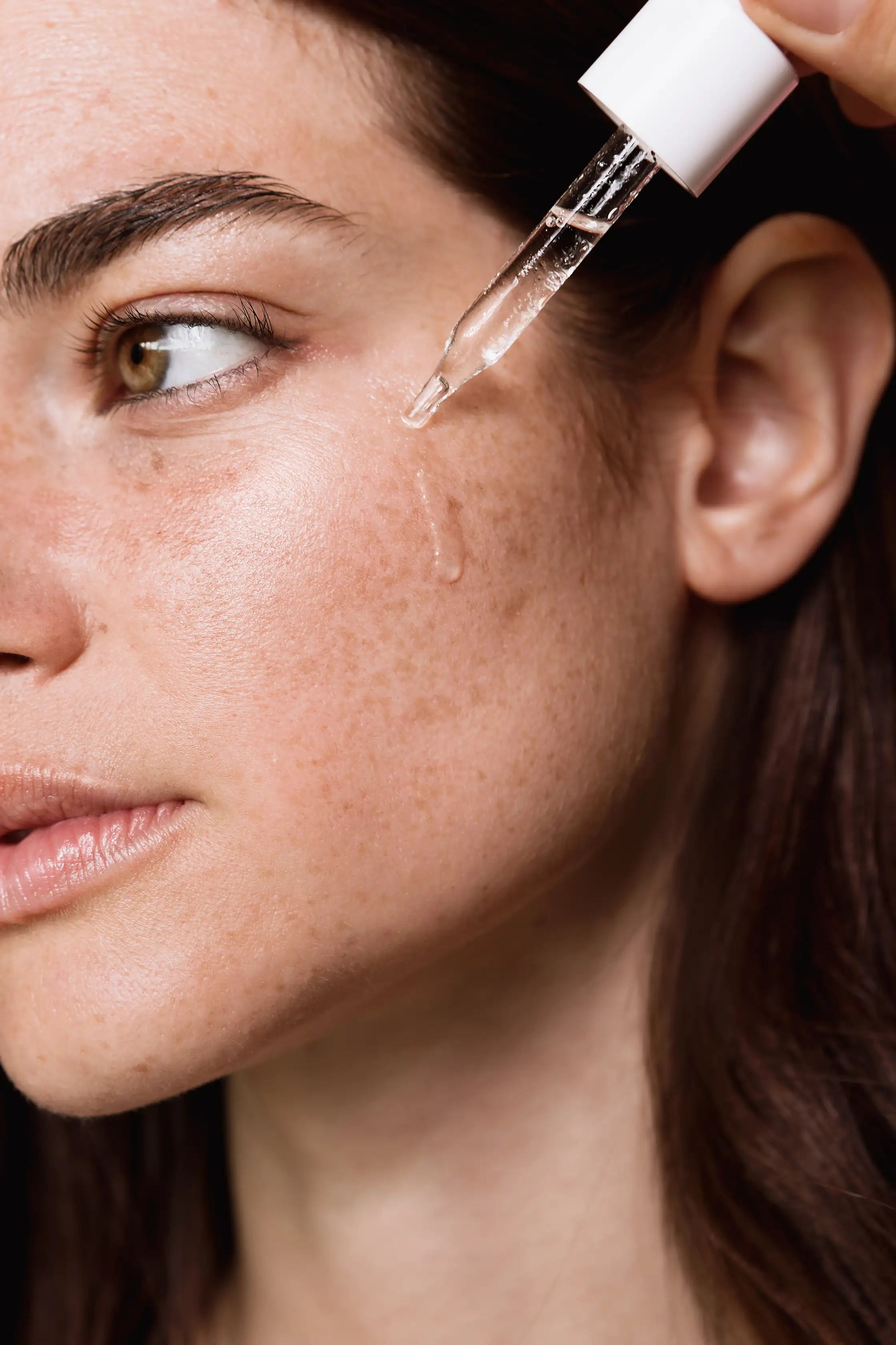 Modelo aplicando el sérum con vitamina C The Daily Radiance Treatment sobre la piel.